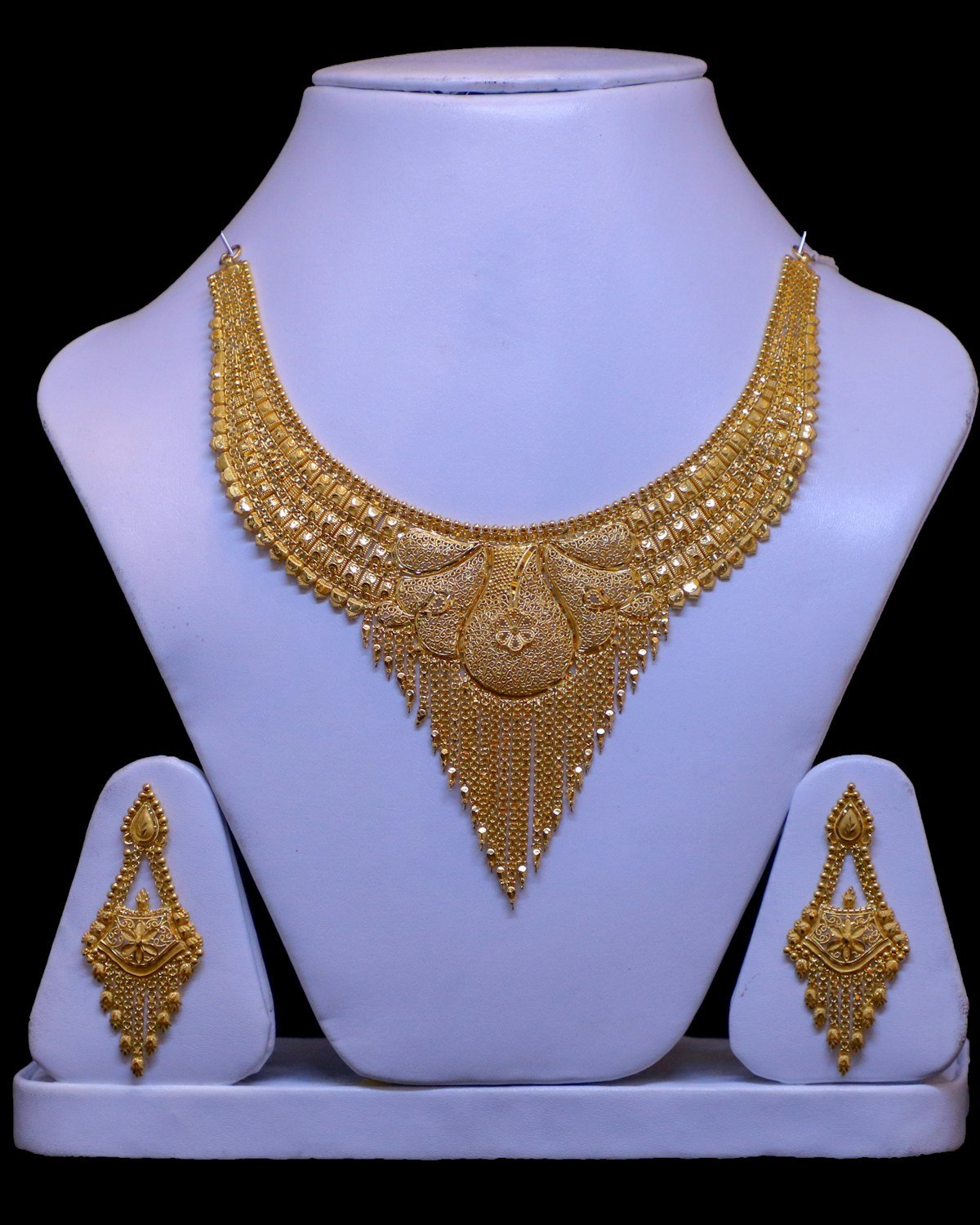 Gold necklace and earring set on a display stand